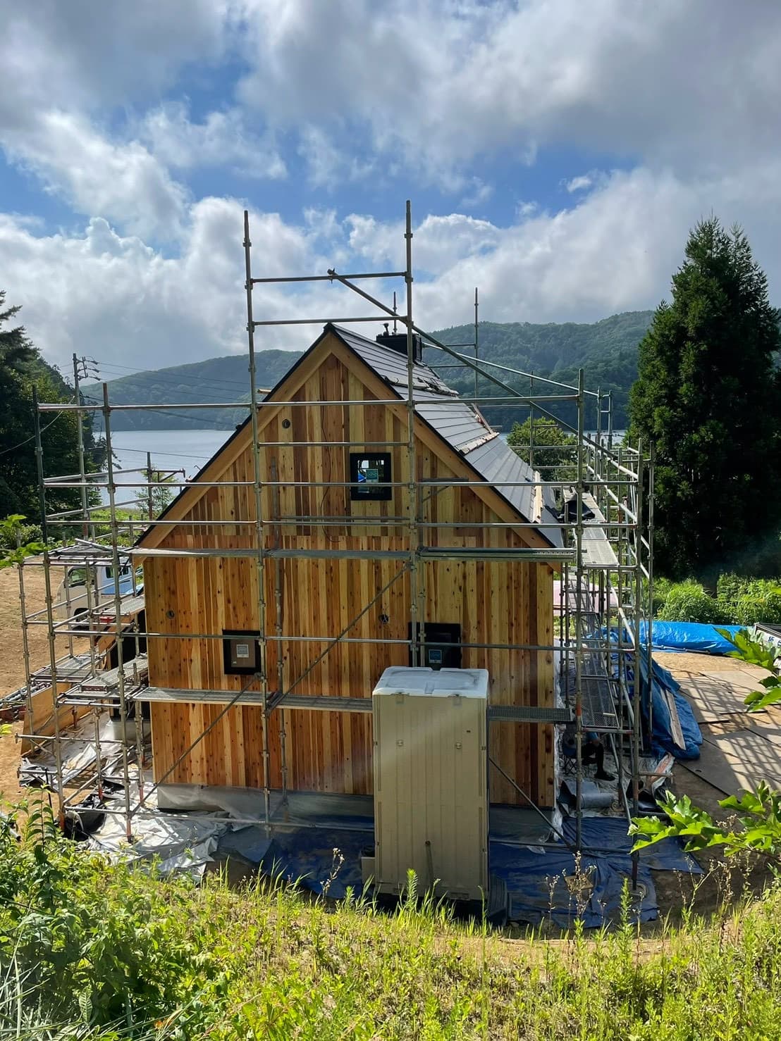 足場に囲まれた建設途中の木造キャビンと三角屋根