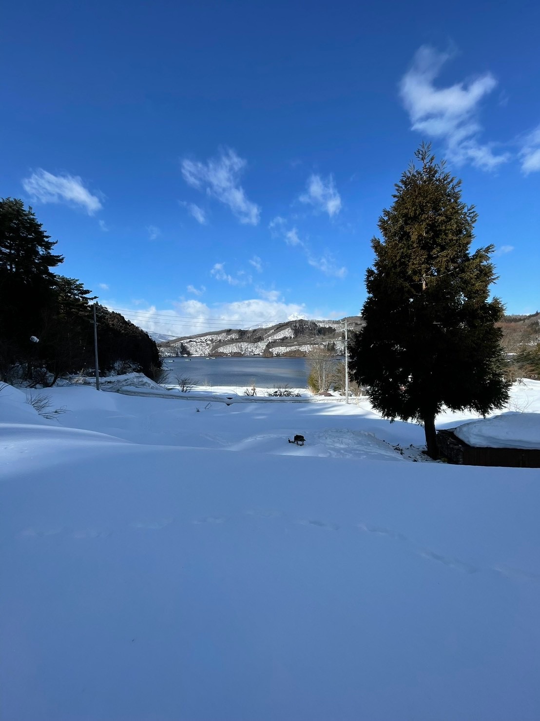 雪に覆われた敷地から望む冬の野尻湖と青空